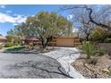 Property featuring desert landscaping, a circular driveway, and mature trees, enhancing its natural setting at 11177 Twilight Times Ct, Las Vegas, NV 89135