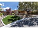 Attractive home exterior with a lush, green front lawn, mature tree, and stone accents enhancing curb appeal at 11177 Twilight Times Ct, Las Vegas, NV 89135