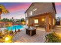 Outdoor living space with a covered patio, dining set, fire pit, and a sparkling pool for relaxing and entertaining at 1200 Dream Bridge Dr, Las Vegas, NV 89144