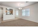 Bright living room with carpet flooring, large windows, and an elegant chandelier fixture at 2550 Evening Twilight Ave, Henderson, NV 89044
