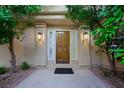 Inviting front entrance with a solid wood door, sidelights, and sconces, framed by lush greenery at 5125 Turnberry Ln, Las Vegas, NV 89113