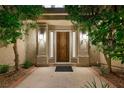 Inviting front entrance with a solid wood door, sidelights, and sconces, framed by lush greenery at 5125 Turnberry Ln, Las Vegas, NV 89113