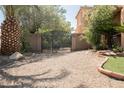 Gravel driveway leading to a gated area with mature landscaping at 7947 Lookout Rock Cir, Las Vegas, NV 89129