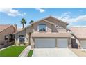 Two-story home featuring a three-car garage, tile roof, desert landscaping, and palm trees on a sunny day at 8714 Las Posas Ave, Las Vegas, NV 89147