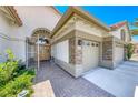 Close-up of the front door with a security gate, brick accents, a beige three-car garage, and brick walkway at 1432 Castle Crest Dr, Las Vegas, NV 89117