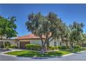Inviting home with a lush lawn, mature trees, and a tile roof, complemented by desert landscaping at 2531 La Cara Ave, Las Vegas, NV 89121