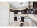 Traditional kitchen with white appliances, dark wood cabinetry, and granite countertops at 5456 Raccoon Valley Ln, Las Vegas, NV 89122