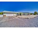 Single story home with a detached garage has gravel yards, rock accents, and a concrete driveway at 6490 Wagon Wheel Ct, Pahrump, NV 89061
