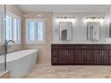 Bright bathroom with a modern tub, tiled floor, and vanity with double sinks and dark wood cabinets at 8437 Apple Hill Ct, Las Vegas, NV 89128