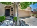 Welcoming front entrance with a charming walkway, mature landscaping, and a two-car garage for convenient parking at 10692 Tulip Valley Rd, Las Vegas, NV 89179
