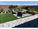 Backyard patio area with pavers, artificial turf, and seating surrounded by landscaped retaining wall at 10836 Montana Blanca Ave, Las Vegas, NV 89166