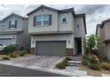Two-story home with gray siding, shuttered windows, gray garage door and brick paver driveway at 10836 Montana Blanca Ave, Las Vegas, NV 89166