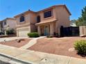 Charming two-story stucco house featuring a two-car garage, arched windows, and low-maintenance desert landscaping at 1482 Flintrock Rd, Henderson, NV 89014