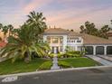 Beautiful home featuring a manicured lawn, lush landscaping, and an impressive driveway surrounded by palm trees at 21 Sawgrass Ct, Las Vegas, NV 89113