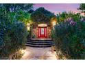 Front door with a brick archway, lush greenery, a red door, and a stone walkway at 3004 Astoria Pines Cir, Las Vegas, NV 89107