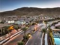 Expansive community view featuring a mountain backdrop, gated entrance, palm trees, and a peek of a pool at 3213 Molinos Dr, Las Vegas, NV 89141