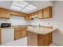 Galley kitchen features wood cabinets, tile floors, light, and appliances, offering ample storage and functionality at 875 Rhinegold Way, Las Vegas, NV 89110