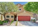 Inviting two-story home featuring a red garage door and well-maintained landscaping with flowering trees at 9370 Corkfish St, Las Vegas, NV 89178