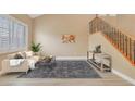 Inviting living room with a comfortable beige sofa, plantation shutters, and staircase at 1405 Peyton Stewart Ct, North Las Vegas, NV 89086