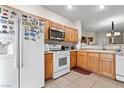 Bright kitchen with wooden cabinets, white appliances, and tiled flooring at 4858 Longshot Dr, Las Vegas, NV 89122