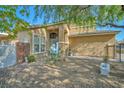 Inviting front yard with desert landscaping, mature trees, and a charming blue door at 1740 Flores Ln, Henderson, NV 89012