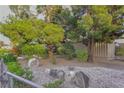 View of front yard featuring mature trees, desert shrubs, and decorative rock ground cover at 2001 E Mcwilliams Ave, Las Vegas, NV 89101