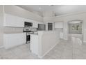 Updated kitchen features white cabinets, stainless steel appliances, breakfast bar, and tile flooring; a chef's dream space at 2158 Shubert Ave, Henderson, NV 89052