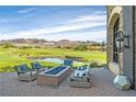A luxury patio with a fire pit and comfortable seating, overlooking a golf course and distant mountains at 44 Alta Cascata Pl, Henderson, NV 89011