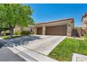 Spacious driveway leading to a two-car garage, complemented by lush green lawns and desert landscaping at 6423 Grayback Dr, North Las Vegas, NV 89084