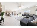 Bright, open-concept living room with a gray sectional couch, ceiling fan, and a view into the kitchen at 1885 Vass Springs Pl, North Las Vegas, NV 89084