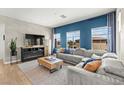Bright living room with large windows, stylish blue accent wall, plush grey sofa, and modern entertainment center at 295 Callen Falls Ave # 2225, Henderson, NV 89011