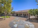 Expansive backyard featuring mature trees, desert landscaping and a paved stone pathway at 401 Obsidian St, Las Vegas, NV 89145