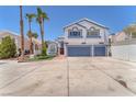 Two-story home featuring a two-car garage, a well-manicured lawn and palm trees on a sunny day at 4871 La Princesa Ct, North Las Vegas, NV 89031