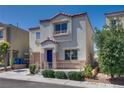 View of a two-story tan stucco house with a blue front door and well-maintained landscaping at 9140 Entrancing Ave, Las Vegas, NV 89149