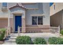 A cozy front porch with a beige railing and trimmed green bushes leading to a vibrant blue front door at 9140 Entrancing Ave, Las Vegas, NV 89149