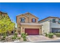 Charming two-story home features a red garage door, brick driveway, and well-maintained landscaping at 9229 Brayden Bay St, Las Vegas, NV 89178