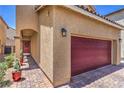 Home's exterior displays a red garage door, a matching front door, and a brick driveway at 9229 Brayden Bay St, Las Vegas, NV 89178