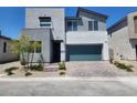 Modern two-story home featuring a gray stucco exterior, brick driveway, and a two-car garage at 10021 Locking Biner Ave, Las Vegas, NV 89166