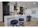 Stylish kitchen featuring contrasting black and white cabinets, a marble countertop island with seating, and modern pendant lights at 10025 Netherton Dr, Las Vegas, NV 89134
