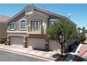 Two-story home featuring neutral stucco, three-car garage, balcony, and mature trees set against a clear sky at 1073 Pleasure Ln # 2, Henderson, NV 89002