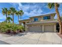 Charming two-story home showcasing a tile roof, three-car garage, and beautiful palm tree landscaping at 2440 Ping Dr, Henderson, NV 89074