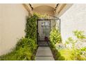 Inviting front entrance with an arched metal gate surrounded by lush greenery, offering a touch of elegance and privacy at 6688 Martinsville Pl, Las Vegas, NV 89110
