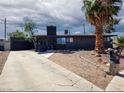 Unique single story house with detached garage, concrete driveway, xeriscaping, and a palm tree at 709 Evergreen Cir, Las Vegas, NV 89107