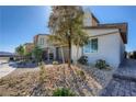 Street view showcasing the home's appealing design, desert rock garden, paved driveway, and proximity to other residences at 9564 Archer Peak Ct, Las Vegas, NV 89143