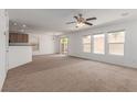 Spacious living room featuring carpet, multiple windows, ceiling fan, and a sliding glass door at 104 Big Cliff Ave, North Las Vegas, NV 89031