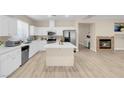 Well-lit kitchen with a cozy fireplace, white cabinets, and an island at 11074 Caramel Crest Ct, Las Vegas, NV 89135
