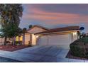 Attractive single-story home featuring a two-car garage, desert landscaping, and a tile roof at twilight at 2725 Cool Lilac Ave, Henderson, NV 89052