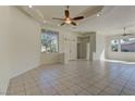 Bright living room boasts neutral walls, tile flooring, ceiling fan and ample natural light through large windows at 2725 Cool Lilac Ave, Henderson, NV 89052