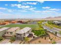 An aerial view of the two-story home featuring an artificial turf backyard and a school with soccer fields nearby at 438 Wind Poppy St, Las Vegas, NV 89138