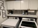Well-organized laundry room with white cabinets and front load washer and dryer at 9485 Supernova Ct, Las Vegas, NV 89123